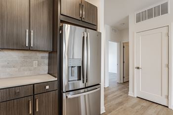 A modern kitchen with a stainless steel refrigerator and wooden cabinets.